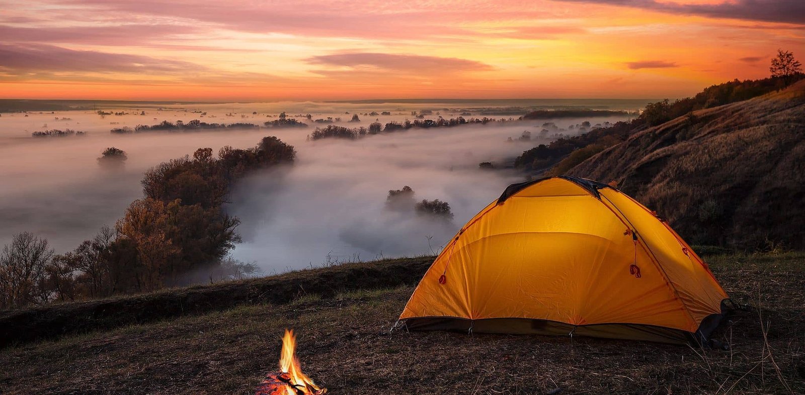 orange-lit-inside-tent-and-fire-over-misty-river-a-2023-11-27-05-09-12-utc